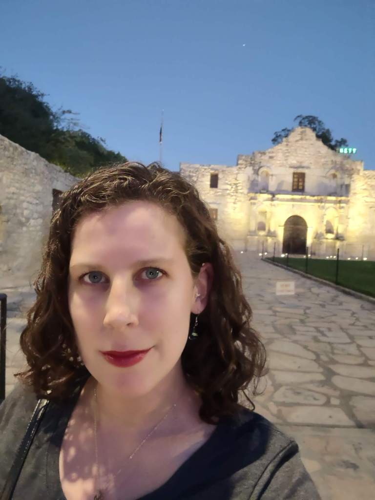 Woman in front of the Alamo at night