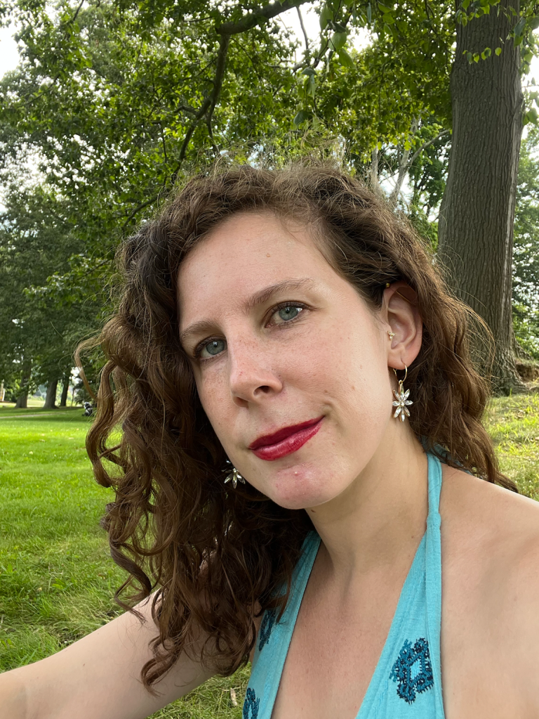 Author sitting on grass underneath trees
