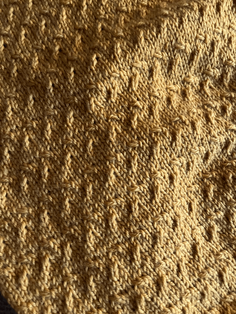 Close-up of knit crosshatch in squash-yellow yarn